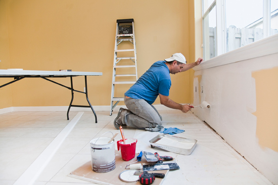 man using roller under window for painting